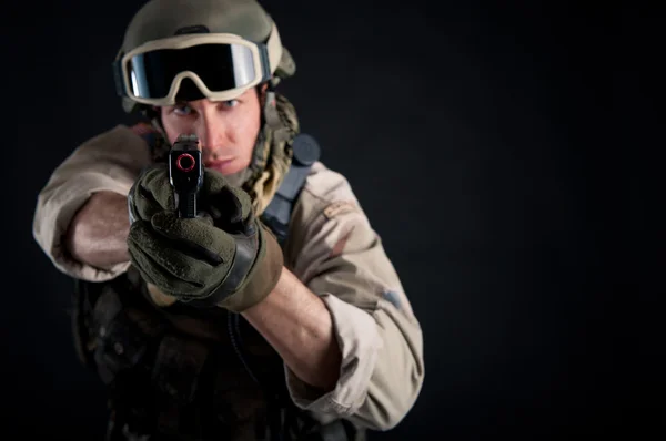 Soldado con arma contra el fondo negro — Stockfoto