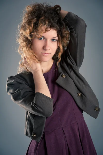 Retrato de bela menina encaracolado posando contra fundo cinza — Fotografia de Stock