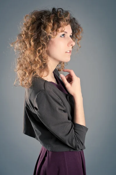 Retrato de sonhando menina encaracolado posando contra fundo cinza — Fotografia de Stock