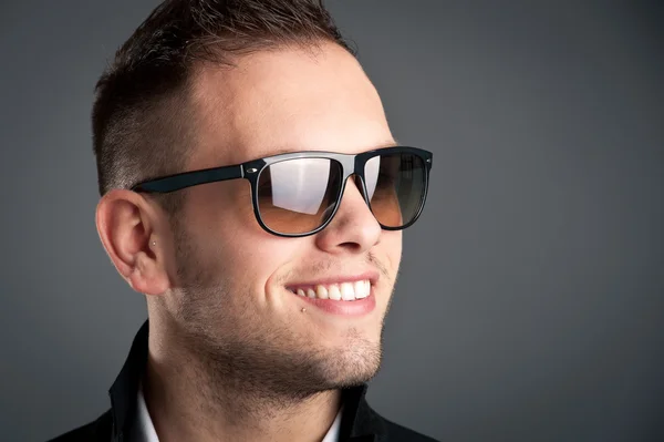 Kleiner Junge mit Sonnenbrille vor grauem Hintergrund — Stockfoto