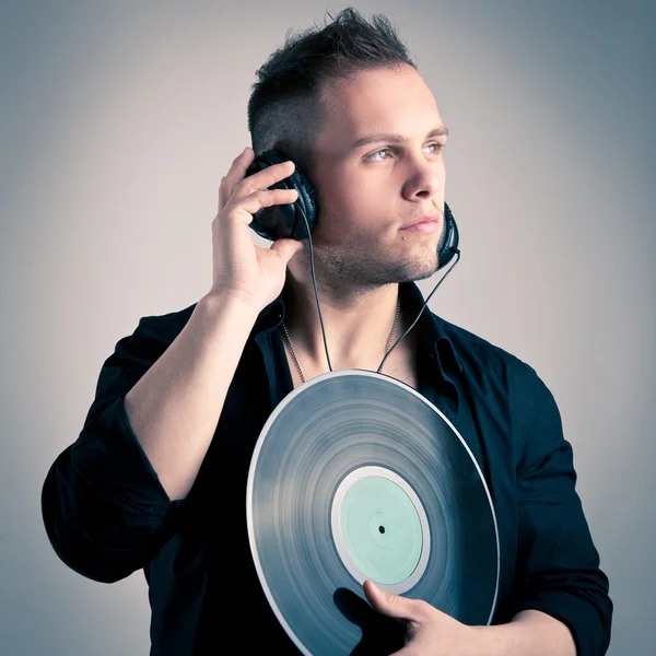 Jonge man aan het werk als dj met oor-telefoons en disc — Stockfoto