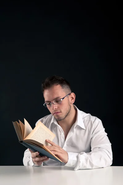 Junger Mann liest ein Buch vor schwarzem Hintergrund mit Kopierplatz für Ihre Nachricht — Stockfoto