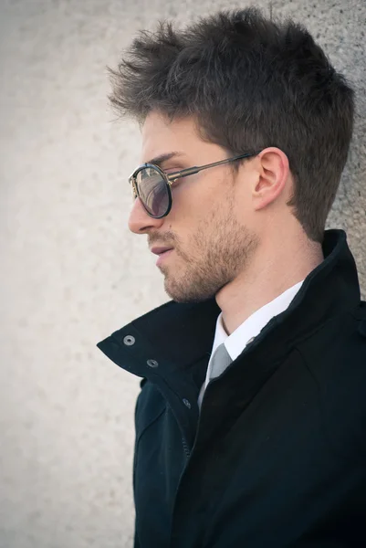 Retrato de homem elegante jovem com óculos de sol contra uma parede — Fotografia de Stock