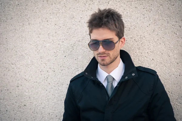 Joven retrato de hombre elegante con gafas de sol contra una pared —  Fotos de Stock