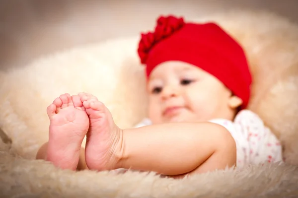 Um bebé de quatro meses com chapéu vermelho. Foco nos pés — Fotografia de Stock