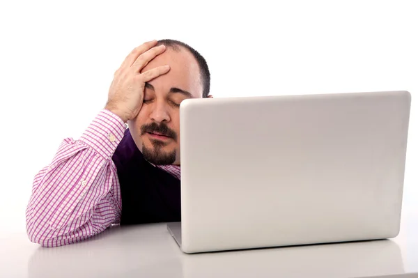 Portrait of a desperate young man looking at laptop against white background — Stock Photo, Image