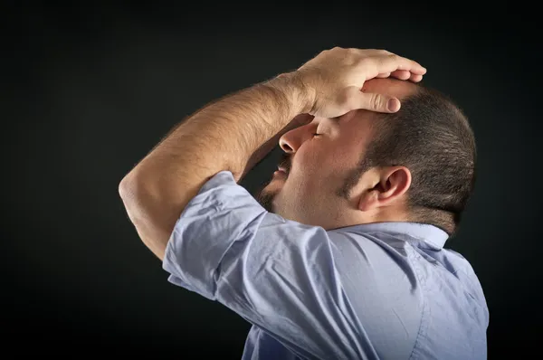 Hombre decepcionado sosteniendo su cabeza con los brazos contra el fondo negro. Imagen conceptual —  Fotos de Stock