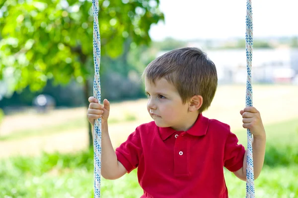 Kleines Kind schwingt an einem sonnigen Tag mit Bäumen im Hintergrund — Stockfoto