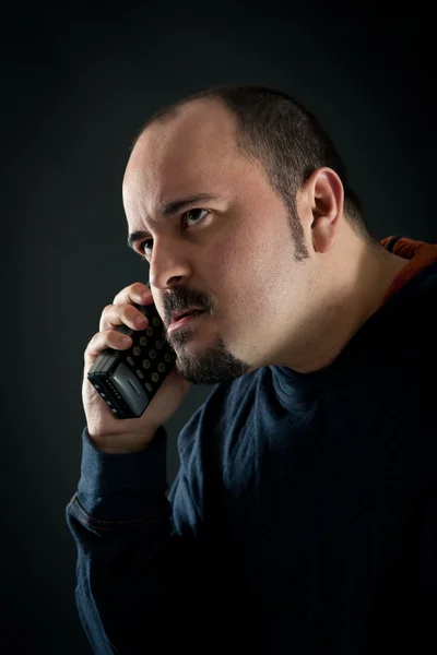 Злой человек разговаривает по телефону на черном фоне — стоковое фото