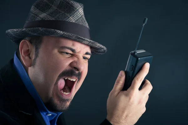 Angry man shouting at the phone against black background — Stock Photo, Image