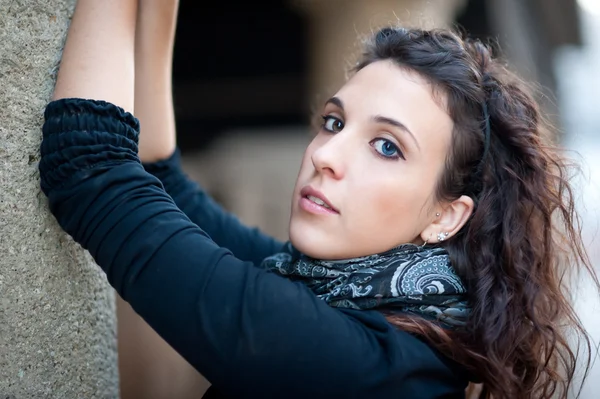 Lány visel kék pulóver támaszkodva egy oszlop portréja — Stock Fotó