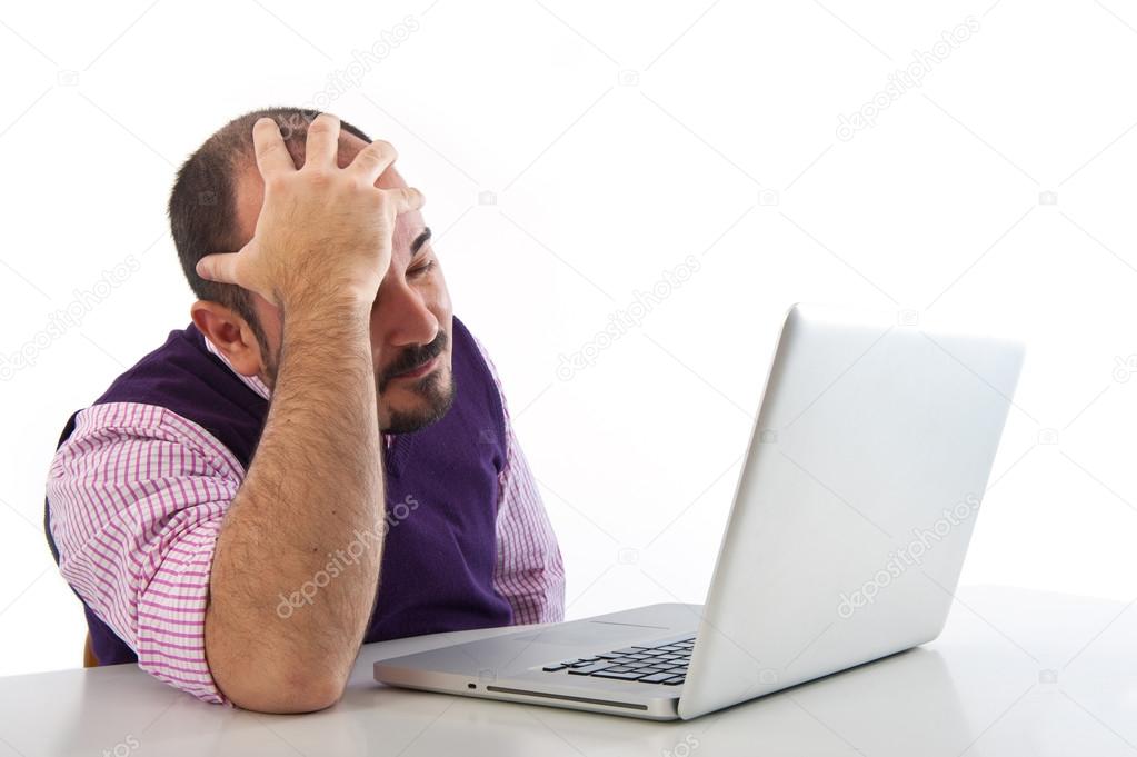 Portrait of a desperate young man looking at laptop against white background