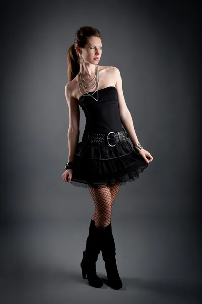 Portret van mooi meisje met zwarte jurk tegen donkere achtergrond — Stockfoto