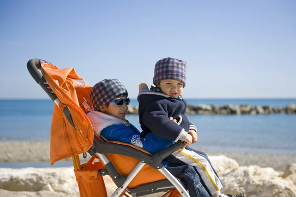 Carrozzina sulla spiaggia con i fratelli — Foto Stock