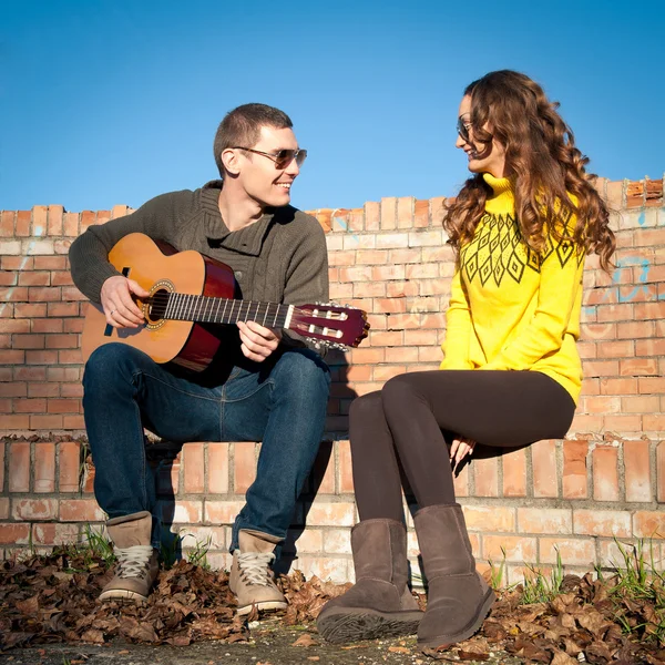 Romántico joven pareja retrato tocando la guitarra bajo el cielo azul —  Fotos de Stock