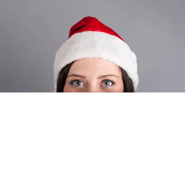 持有广告牌灰色背景上孤立的圣诞老人帽子圣诞女人 — 图库照片
