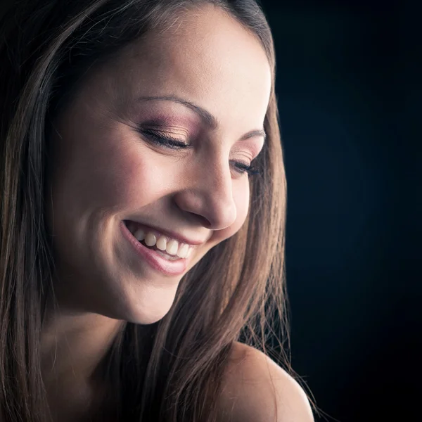 Laughing young woman close up portrait against black background — Stock Photo, Image