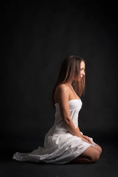 Intimate woman portrait wearing white dress against dark background — Stock Photo, Image