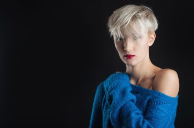 Kendine güvenen kız portre ile Mavi kazak ve siyah arka plan üzerinde izole kırmızı ruj