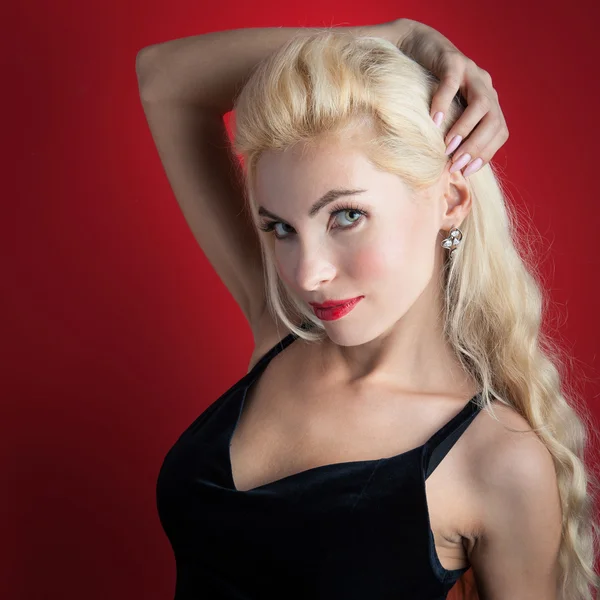 Mooie blonde vrouw close-up portret tegen rode achtergrond — Stockfoto