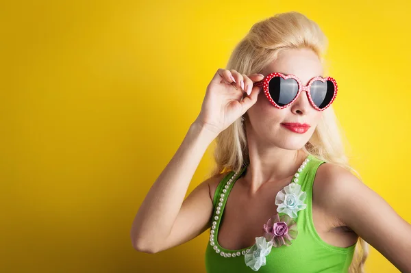 Blonde girl with heart glasses against yellow background — Stock Photo, Image