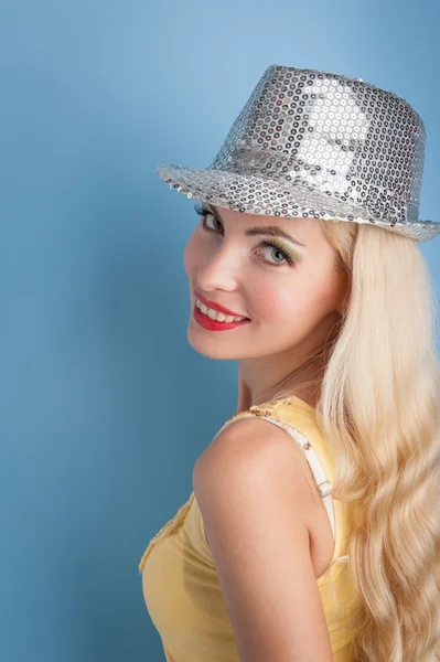 Blondes Mädchen mit silbrig glänzendem Hut vor blauem Hintergrund — Stockfoto