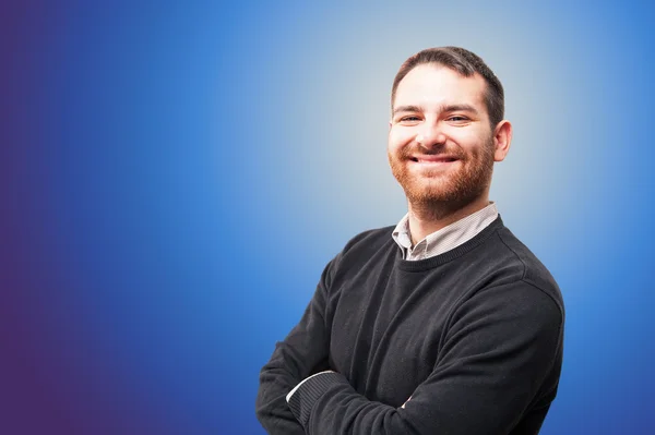 Young man smiling against blue background — Stock Photo, Image