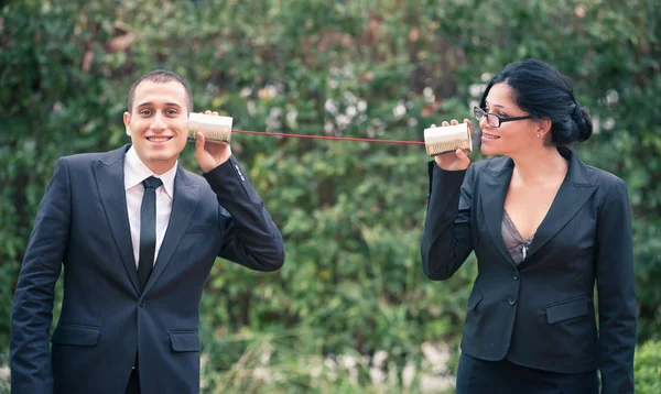 Paar junge glückliche Geschäftsleute und Geschäftsfrauen im Gespräch mit Blechbüchsen-Telefonen — Stockfoto