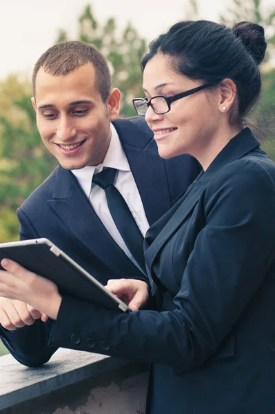 Paar aus Geschäftsmann und Frau schaut im Freien auf Tablet — Stockfoto