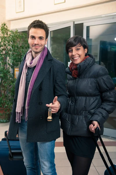 Happy young couple entering in hotel with key of the room — Stock Photo, Image