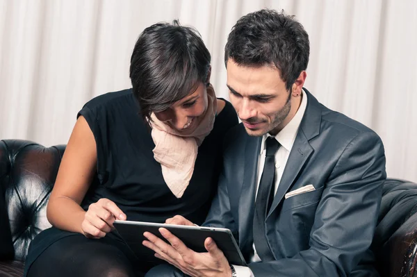 Paar aus Geschäftsmann und Frau schaut auf dem Sofa auf Tablet — Stockfoto