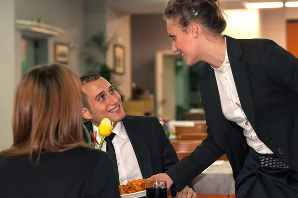 Ungt par äta middag med en servitris som serverar mat på en restaurang — Stockfoto