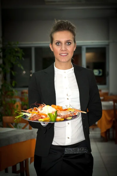 Happy young waitress with food in restaurant — Stock Photo, Image
