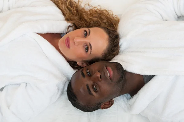 Glückliches junges interracial Paar im Bett liegend, Draufsicht — Stockfoto