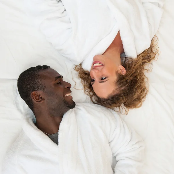 Glückliches junges Paar im Bett liegend, einander anschauend, Draufsicht — Stockfoto