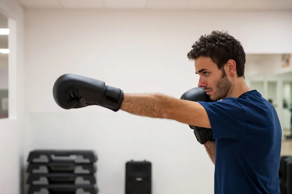 Młody człowiek wykonujący rezygnować Rękawice bokserskie w siłowni — Zdjęcie stockowe