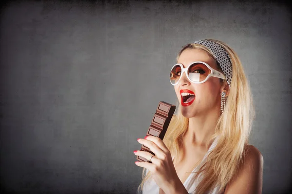 Blonde woman portrait eating chocolate against grunge background — Stock Photo, Image