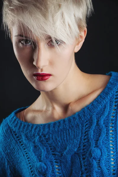 Självsäker tjej stående med blå tröja och rött läppstift isolerade mot svart bakgrund — Stockfoto