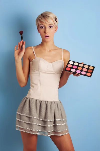 Žena s make-up štětce a barvy modré pozadí — Stock fotografie