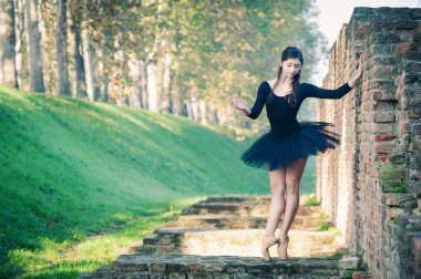 genç güzel balerin antik duvar boyunca açık havada dans