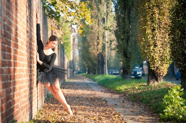 Jeune belle ballerine dansant à l'extérieur le long d'un mur de briques — Photo