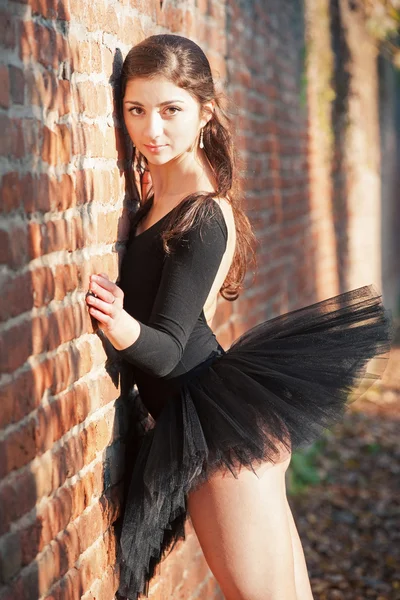 Молодая красивая балерина позирует на открытом воздухе вдоль кирпичной стены — стоковое фото