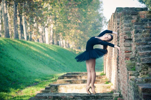 Genç güzel balerin antik duvar boyunca açık havada dans — Stok fotoğraf
