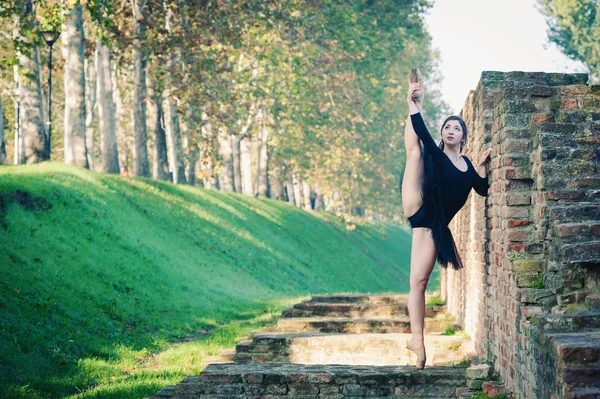 Unga vackra ballerina dansa utomhus längs den gamla väggen — Stockfoto