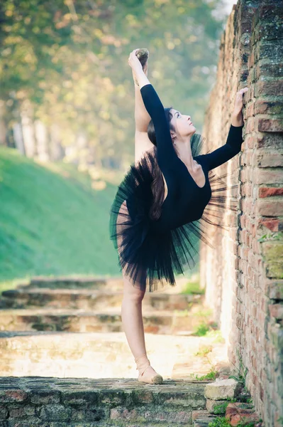 Молодая красивая балерина танцует на открытом воздухе вдоль древней стены — стоковое фото
