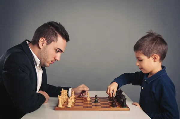 Άνθρωπος και παιδί παίζει σκάκι, απομονώνονται σε σκούρο φόντο — Φωτογραφία Αρχείου