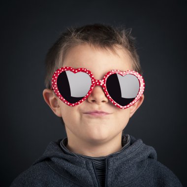 siyah arka plan üzerinde kalp gözlük gülümseyen çocuk portresi