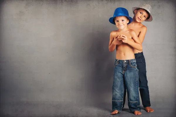 Giovani fratelli che giocano insieme con il cappello. Studio ritratto con sfondo grigio — Foto Stock