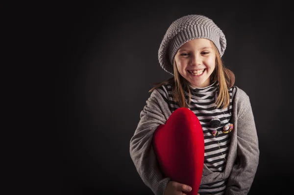 Lovely young girl with red heart on black background — Stock Photo, Image