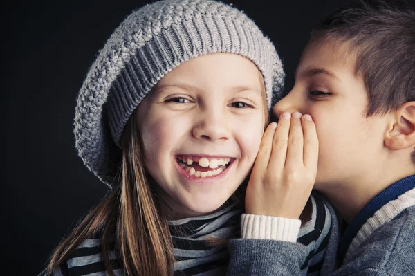 Couple of kids whispering on black background — Stock Photo, Image